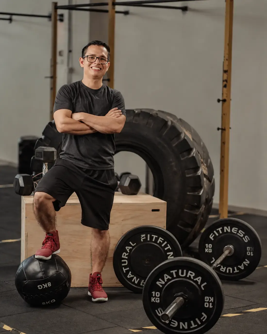 Ray, entrenador personal, sonriendo de brazos cruzados en el gimnasio